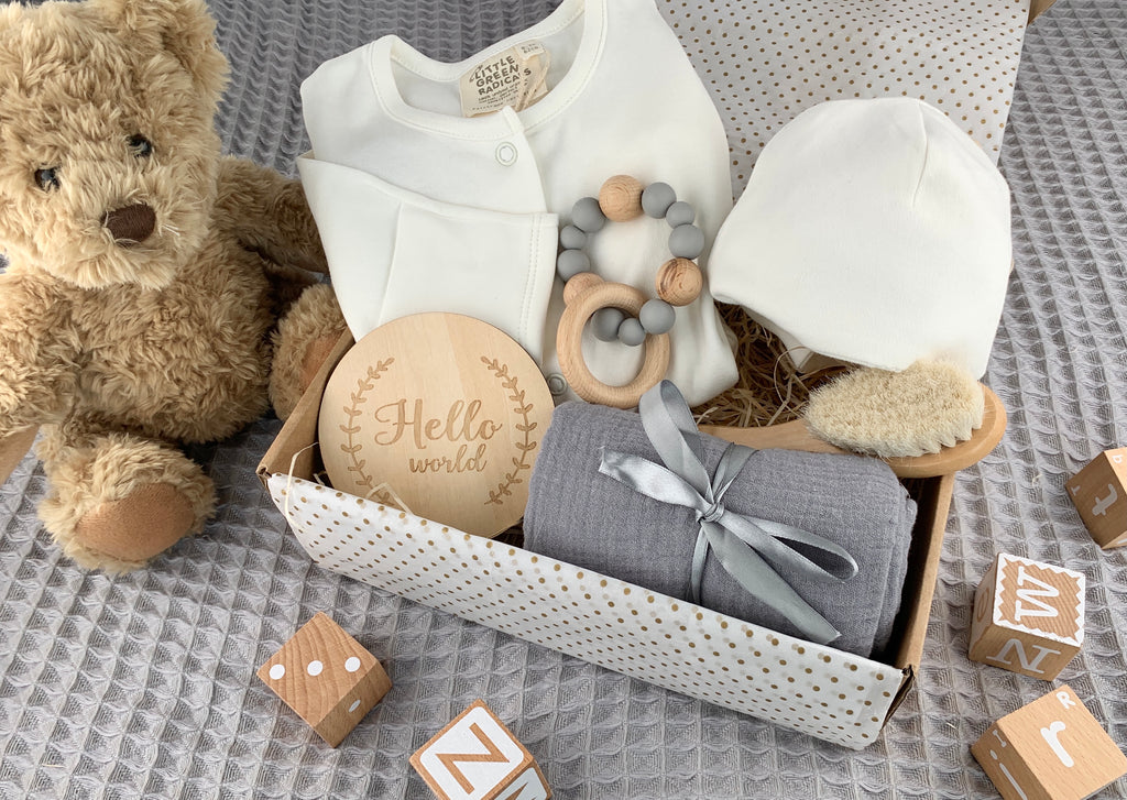 Unisex Baby Gift Set containing white 100% organic cotton baby grow and hat, wood and silicon grey teether, wooden soft bristle baby brush, Hello World wooden announcement disc and 100% cotton muslin in grey