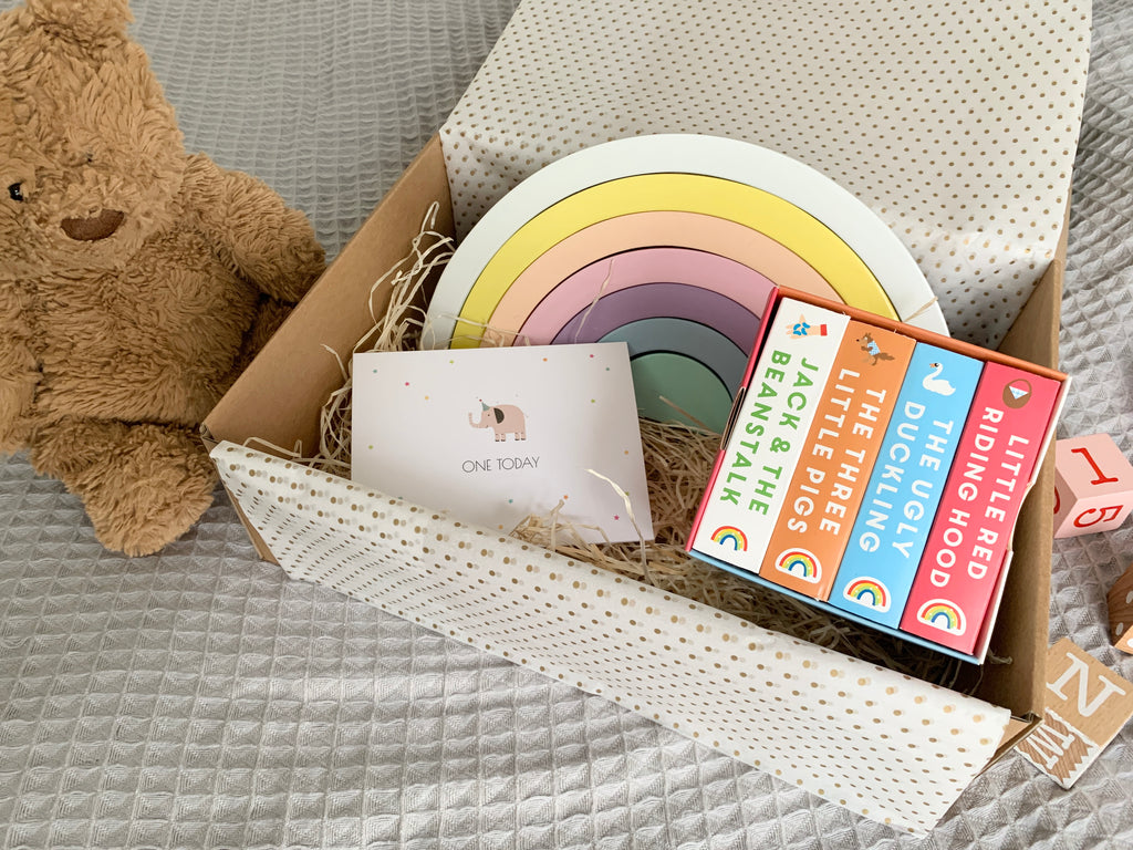 First birthday gift box which includes a birthday card, wooden fairtrade pastel rainbow and fairytale boards books