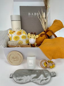 Ultimate Sunshine Mama Baby gift set containing Baby record book journal in grey, ceramic coffee cup by Frank Green, sunshine baby grow by Angel Dear, yellow giraffe crochet rattle, 100% cotton mustard dribble bib and muslin, wooden soft bristle brush, Hello world wooden announcement disc, Still candle by Universal Soul Company, wood and silicon yellow teether and grey 100% silk eye mask
