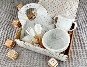 First food weaning set in gift box, including white and grey marble effect bib, bowl, sipy cup and fork and spoon.